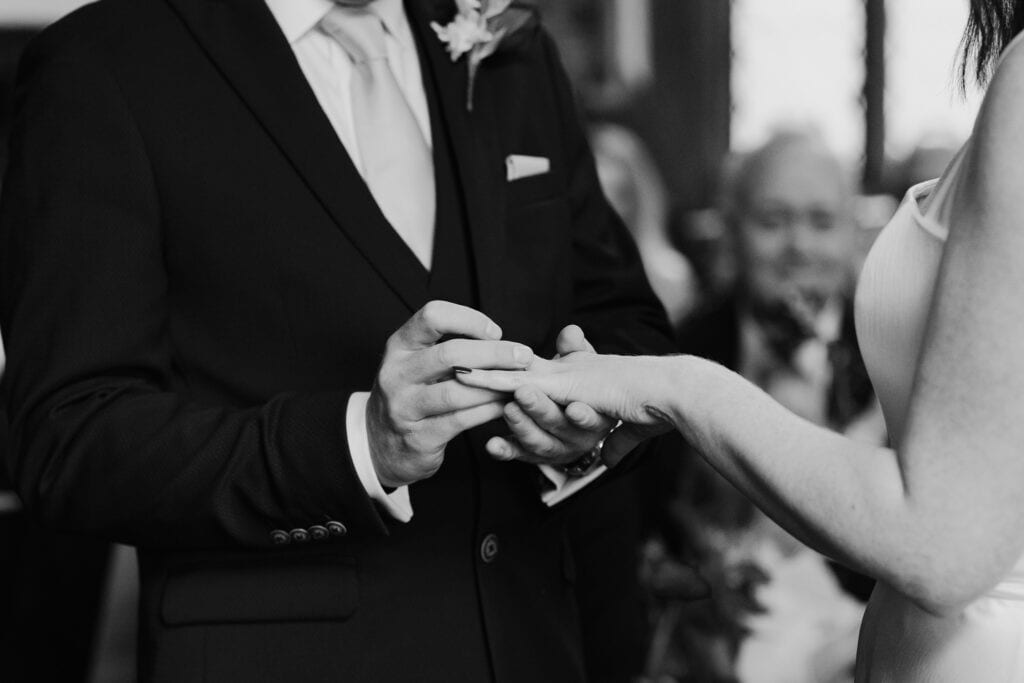 Close-up of the groom gently placing the wedding ring on the bride’s finger during a romantic Birtsmorton Court ceremony. This timeless black and white wedding photo captures the emotional exchange of vows in an intimate and elegant setting. A perfect moment of love and commitment, beautifully documented by a Buckinghamshire wedding photographer specialising in candid and storytelling wedding photography.