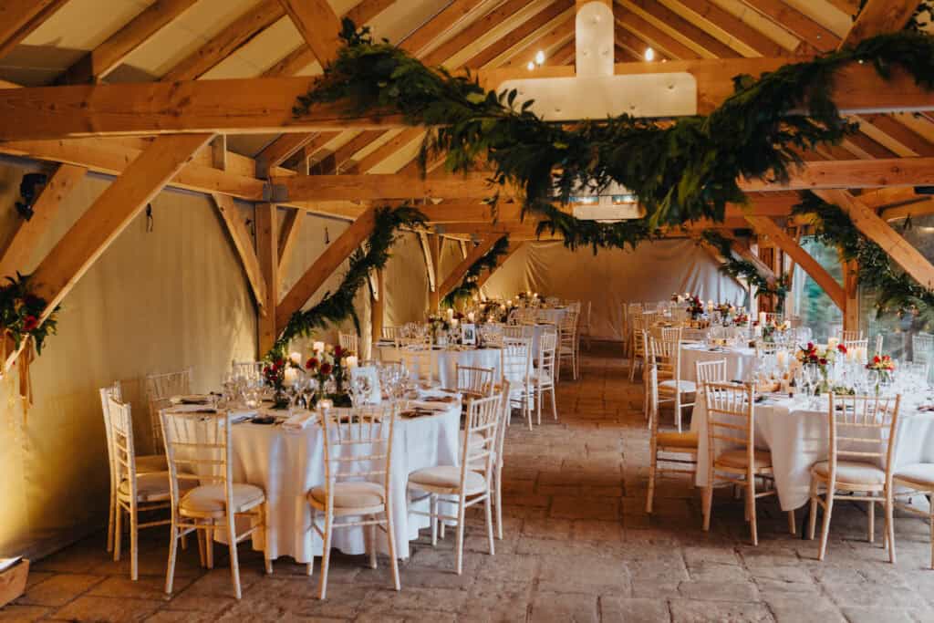 Stunning winter wedding reception at Birtsmorton Court – a beautifully decorated barn with rustic wooden beams, festive garlands, and candlelit tables. The intimate and cosy atmosphere creates the perfect setting for a magical Cotswolds wedding celebration.