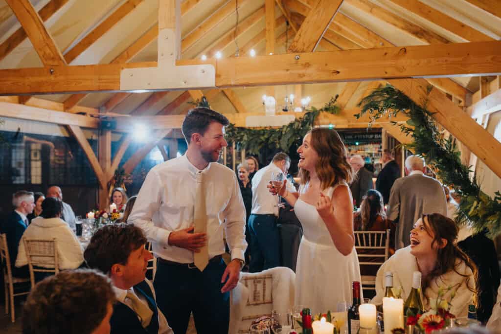 Candid wedding reception moments at Birtsmorton Court – the bride shares a joyful laugh with guests in the beautifully decorated winter wedding setting. A heartwarming celebration filled with love, laughter, and elegant rustic charm in the Cotswolds.