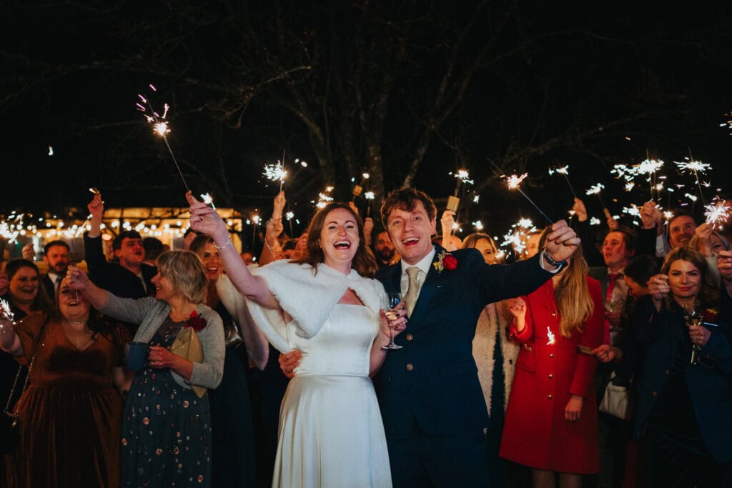 Bride and groom’s magical sparkler exit at Birtsmorton Court – a joyous winter wedding celebration in the Cotswolds. Surrounded by family and friends, the newlyweds light up the night with sparklers, laughter, and love. A perfect wedding photography moment capturing the essence of a festive evening.