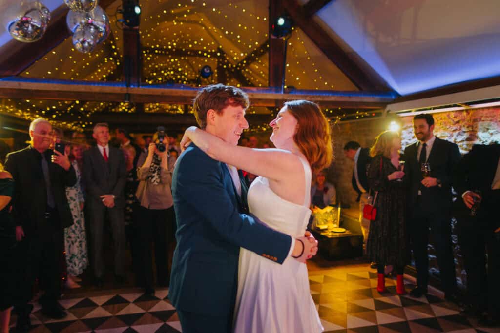 Romantic first dance at Birtsmorton Court – the newlyweds share a joyful moment under twinkling fairy lights, surrounded by loved ones. A beautifully intimate wedding reception in the Cotswolds, perfect for capturing emotional and timeless wedding photography.