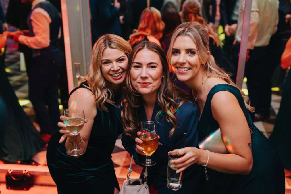 Bridesmaids and guests enjoying the evening party at a winter wedding at Birtsmorton Court. Laughter, drinks, and dancing under twinkling lights capture the joy of this Cotswolds wedding celebration.