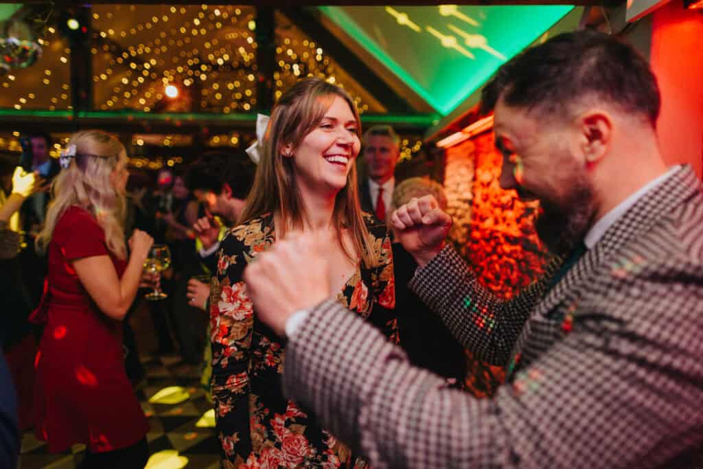 Vibrant wedding party at Birtsmorton Court with guests dancing under sparkling lights. A joyful evening celebration full of laughter, music, and festive energy at this stunning Cotswolds winter wedding venue.