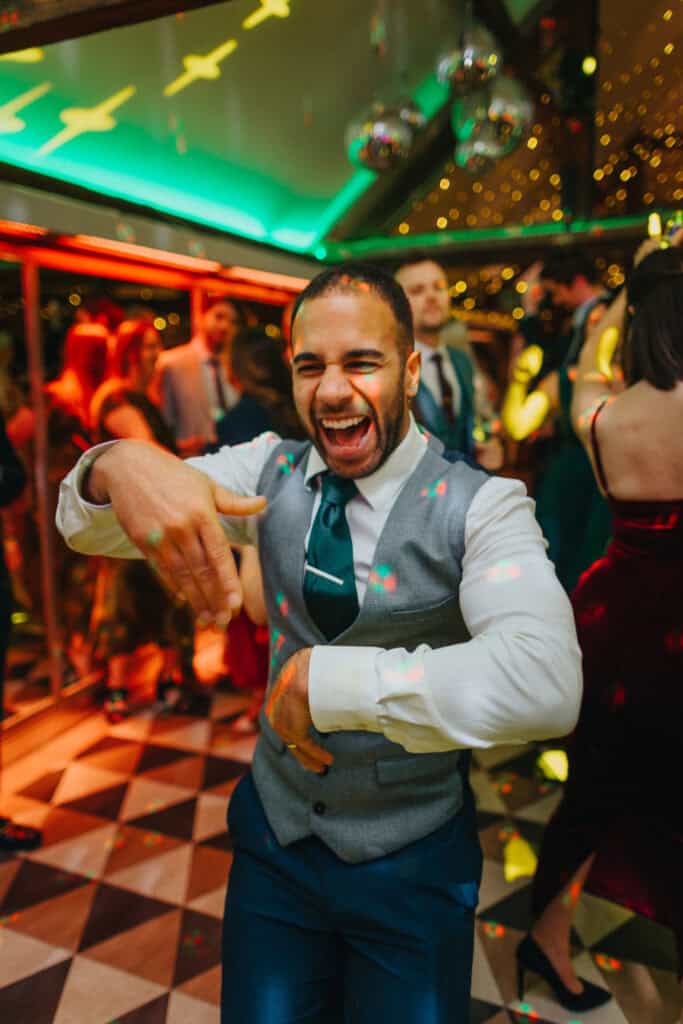 Guest showcasing energetic dance moves at the evening wedding reception at Birtsmorton Court. The dance floor comes alive with vibrant lighting, laughter, and celebration, capturing the joyful atmosphere of a winter wedding in the Cotswolds