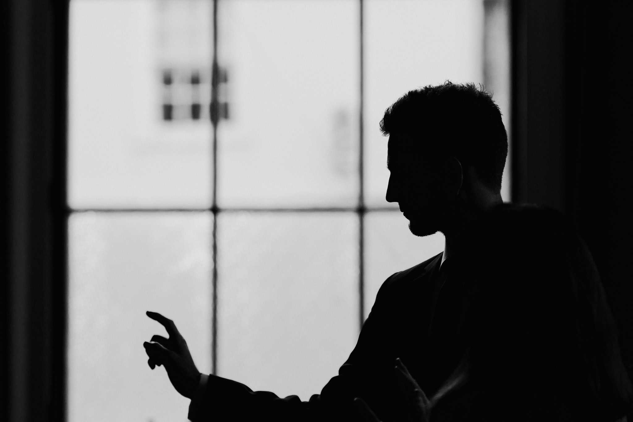 A striking black and white silhouette of the groom against a window at Woodstock Town Hall. A creative and artistic wedding portrait capturing timeless elegance and emotion.