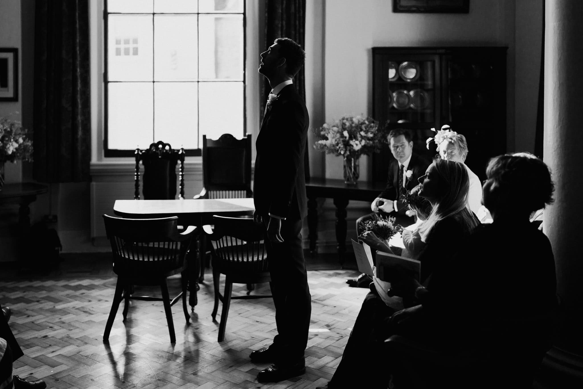 Black and white photo of the groom standing in anticipation before the ceremony at Woodstock Town Hall. A powerful and emotional wedding moment capturing raw feelings and timeless elegance.