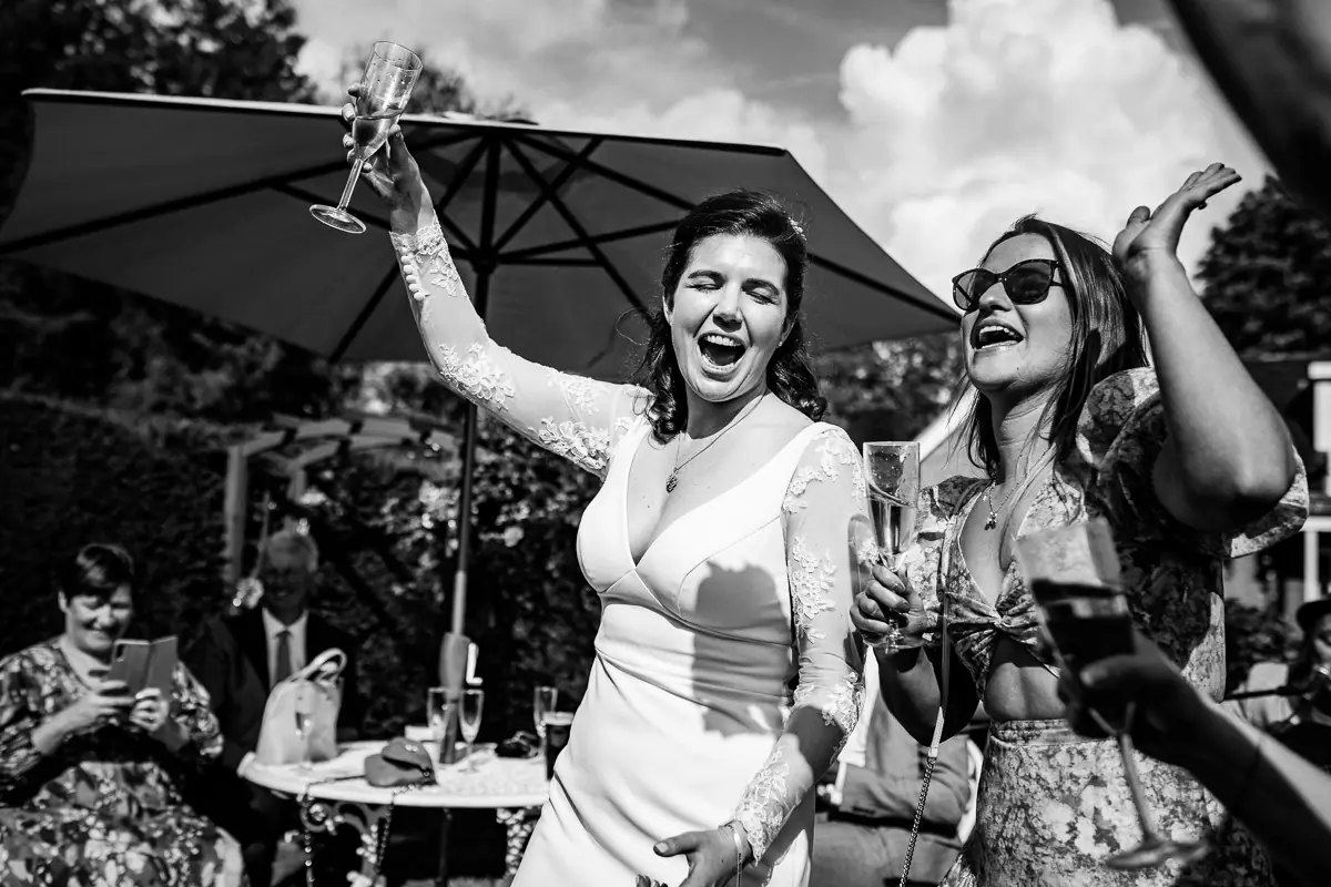 A spontaneous, joyful moment as the bride raises her glass during an outdoor garden celebration. Candid, emotional and full of summer energy.