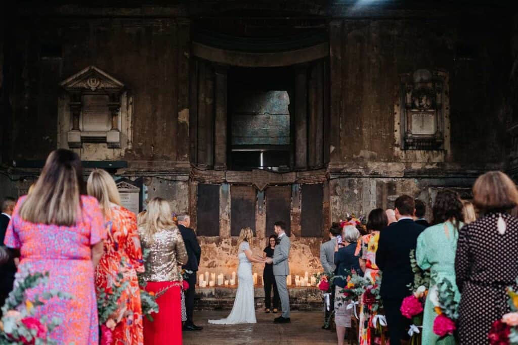ceremonia ślubna w Asylum Chapel w Londynie z gośćmi i industrialnym wnętrzem kaplicy