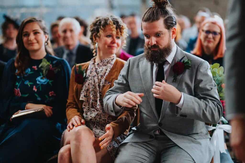 świadek wyciąga obrączki z kieszeni podczas ceremonii ślubnej w Asylum Chapel w Londynie
