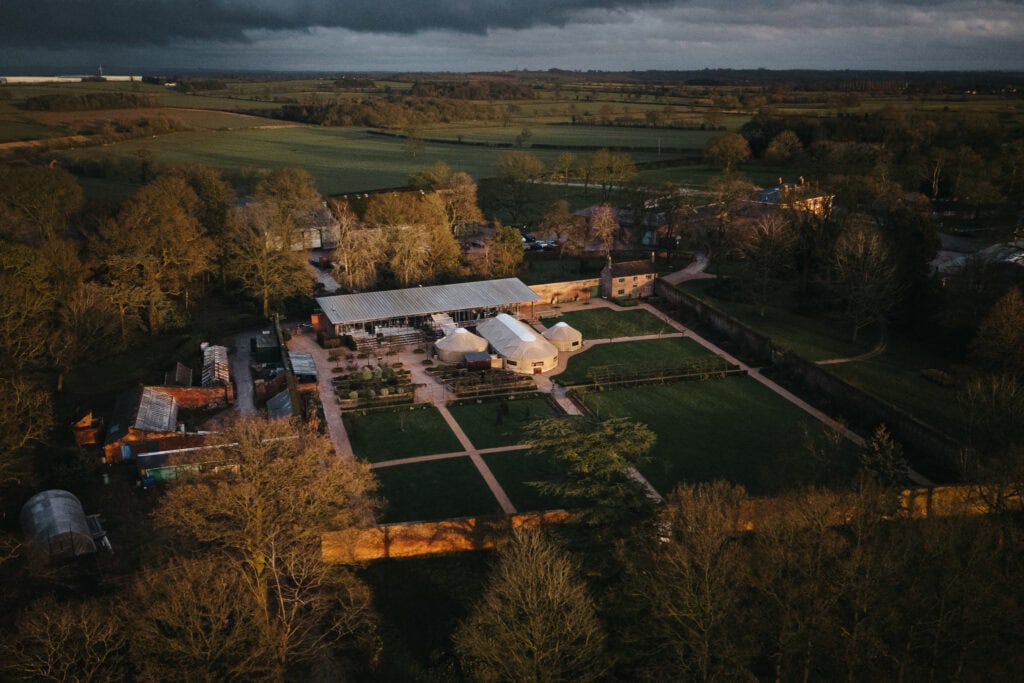 Aerial view of Thorpe Garden wedding venue with gardens, yurt, and barn surrounded by countryside during a winter wedding day.