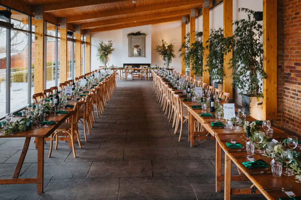 Thorpe Garden wedding venue with long wooden tables, green napkins, floral arrangements, and natural light ready for the wedding breakfast.
